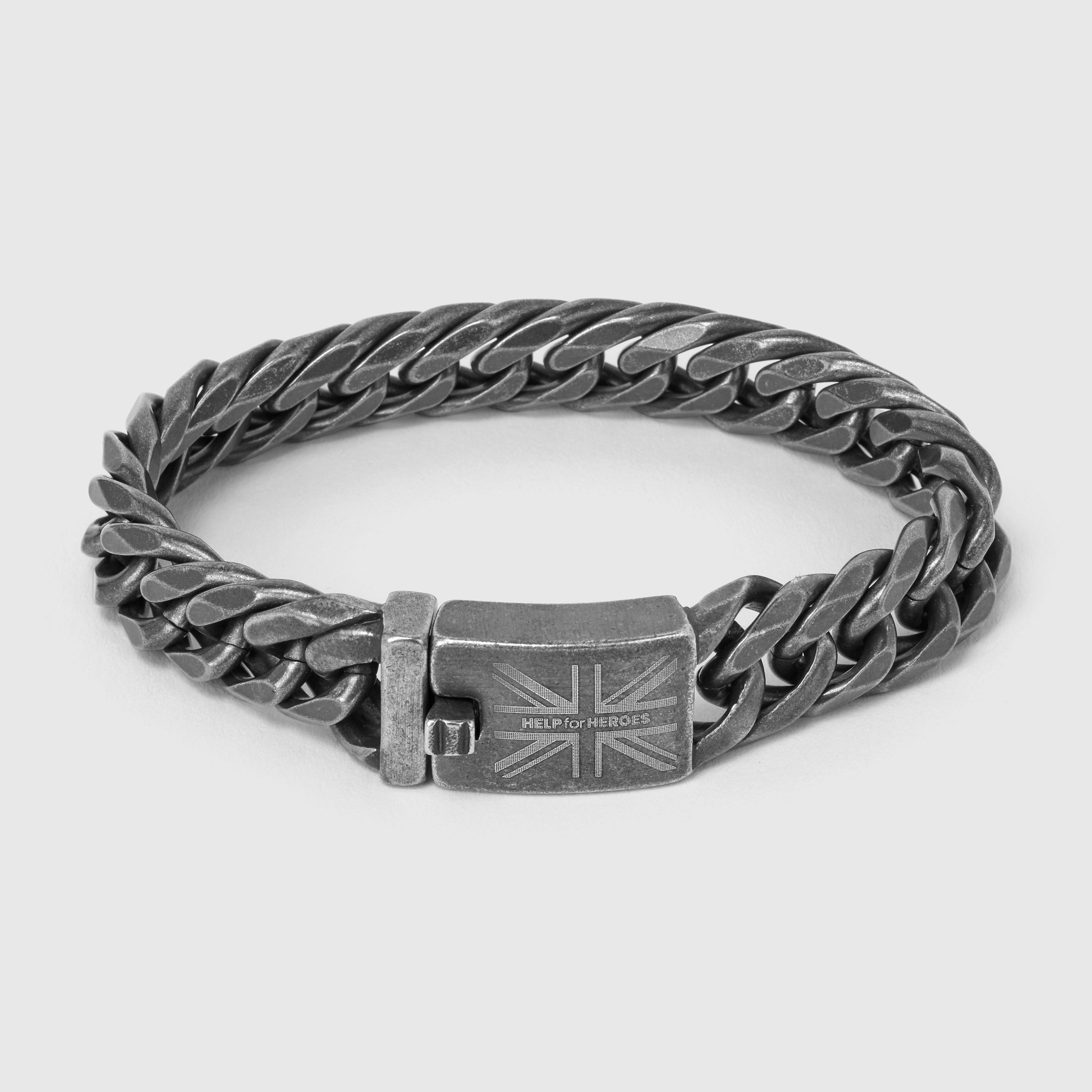A flat lay image of a gunmetal curb chain bracelet with a clasp featuring the Union Jack and Help for Heroes logo