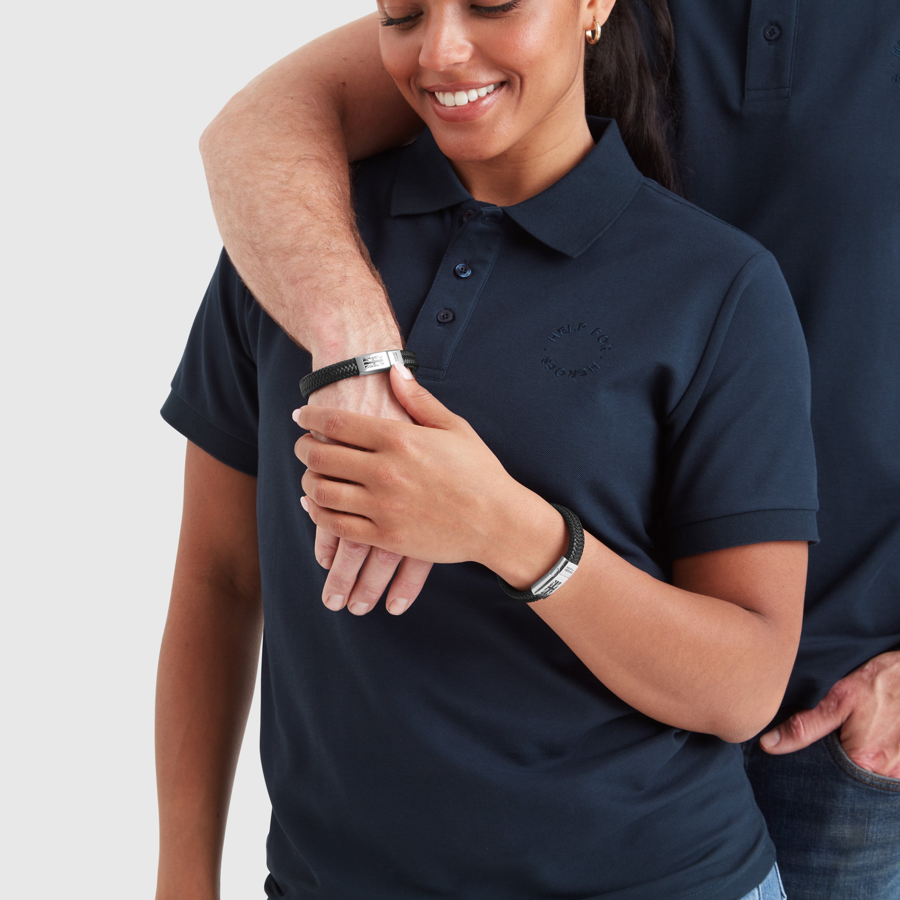 A model wearing a black leather chunky bracelet with a clasp featuring the Union Jack flag and the 'Help for Heroes' logo.