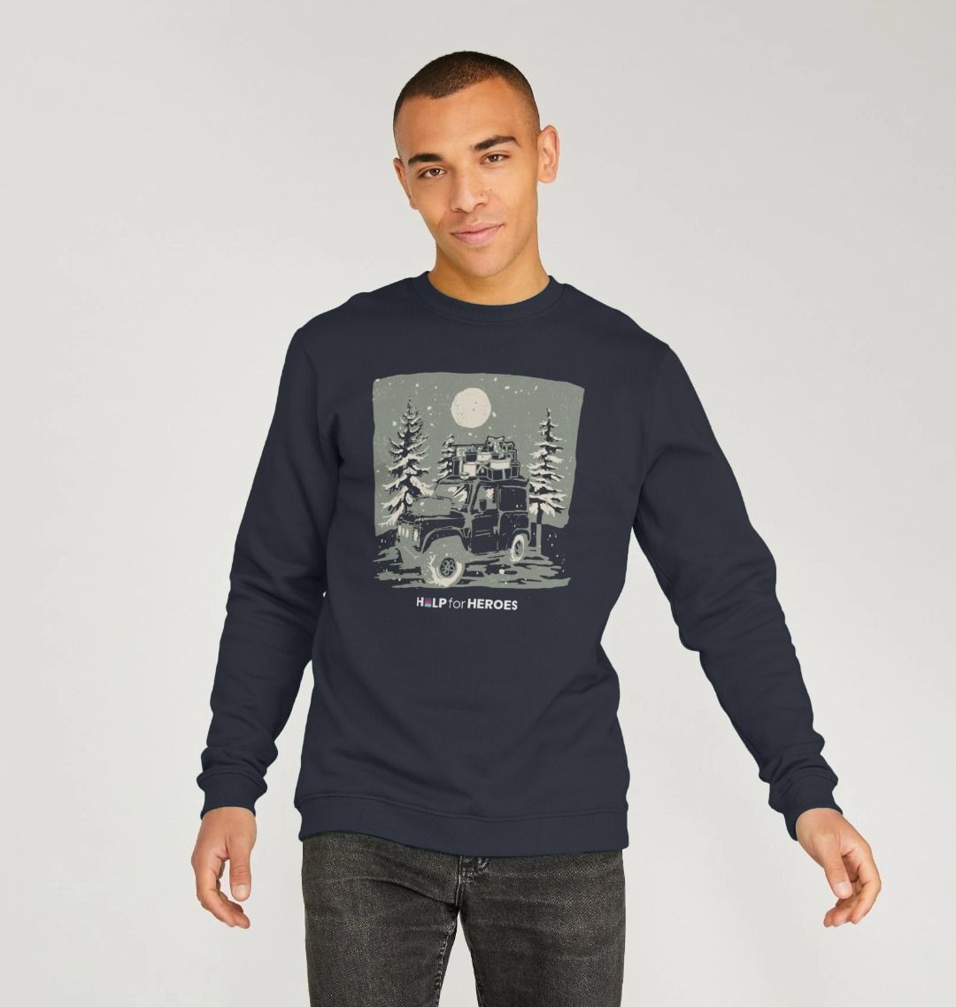 Model wearing Help for Heroes Christmas sweatshirt, with an image of a Land Rover carrying Xmas presents through a snowy tree scene