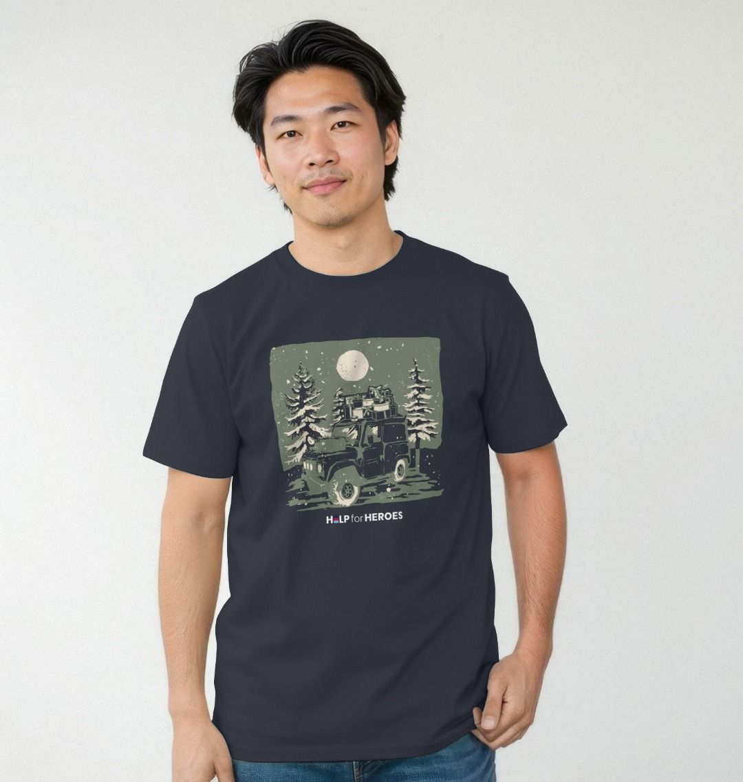 Model wearing a navy Help for Heroes tshirt, featuring a Land Rover carrying Xmas presents through Christmas trees and a snowy scene