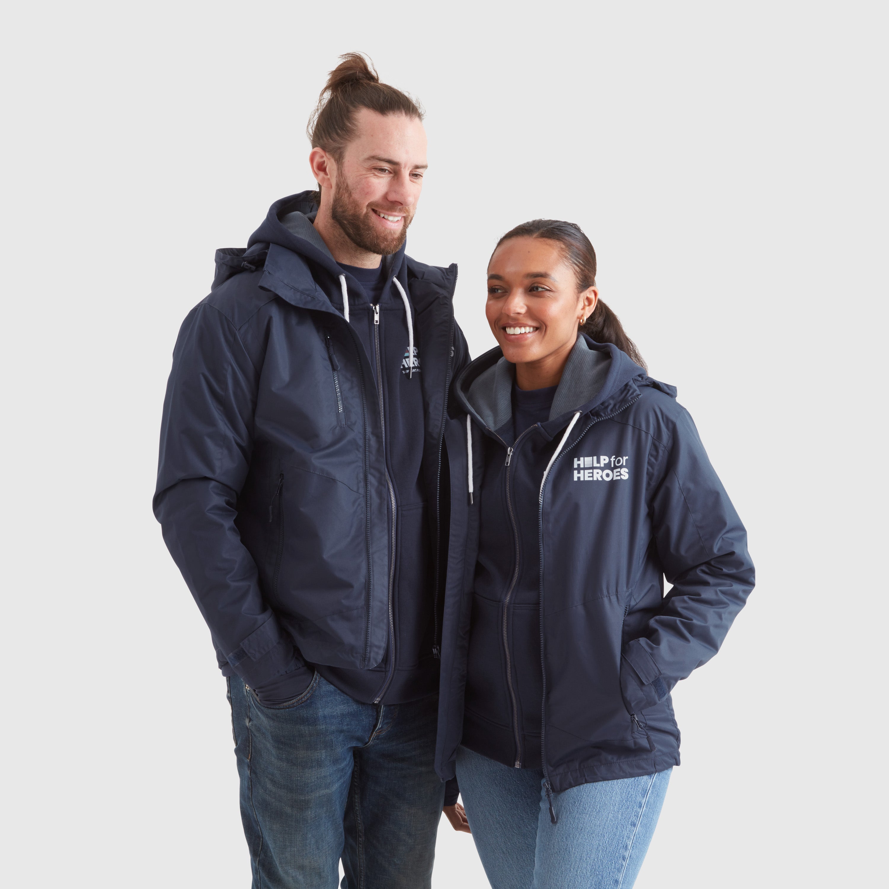 A male and a female model wearing navy waterproof coats with Help for Heroes logo on the chest