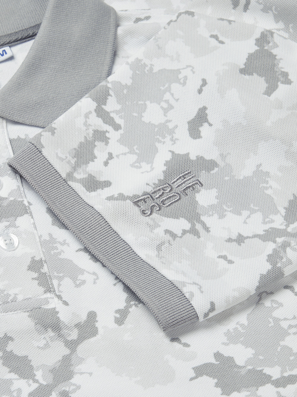 Close up image of embroidered Help for Heroes logo on the sleeve of grey camo jersey polo