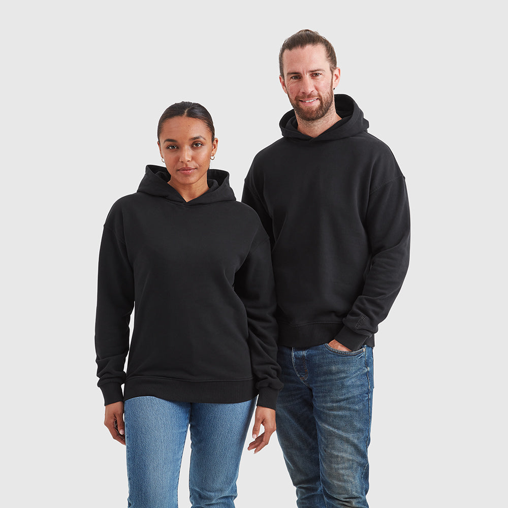 Two models wearing relaxed fit pullover black hoodie. Featuring a subtle embroidered Help for Heroes logo on the sleeve