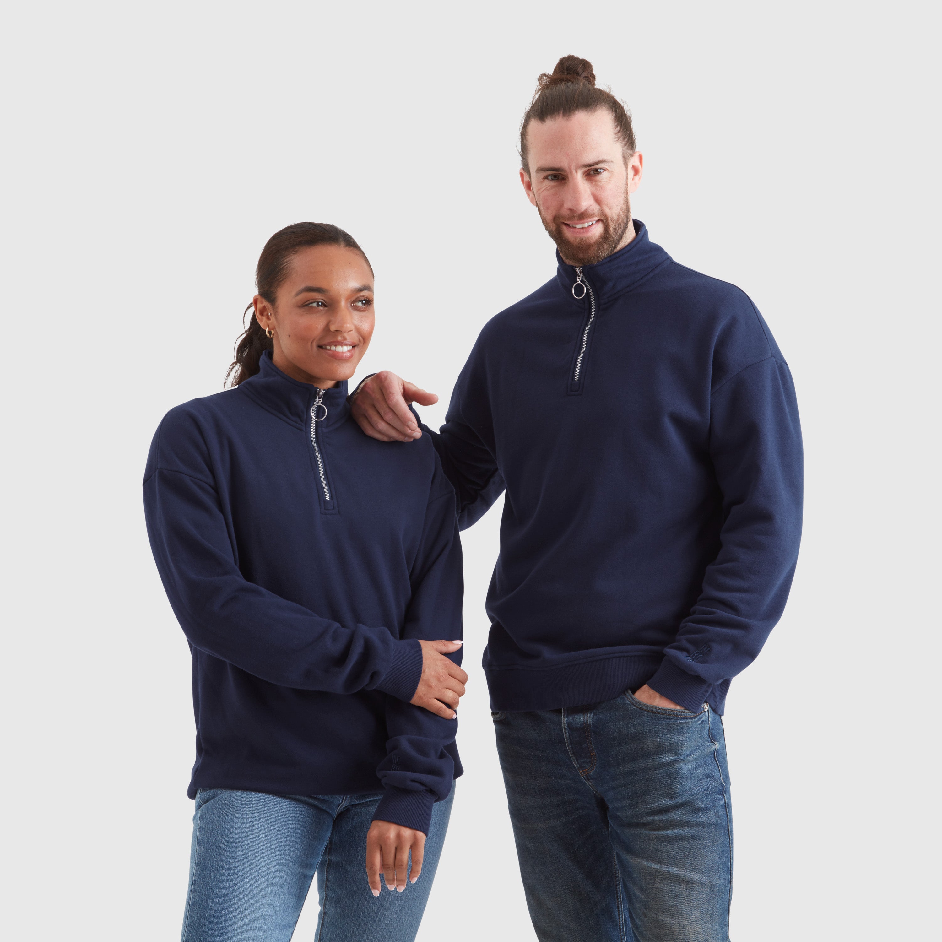 A male and a female model wearing washed navy half zip sweatshirts, featuring an embroidered Help for Heroes logo on the sleeve
