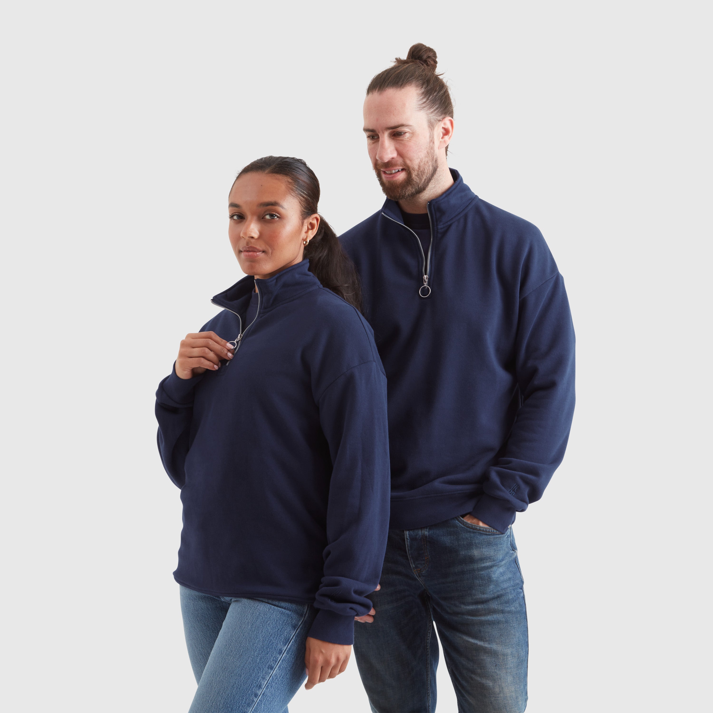 A male and a female model wearing washed navy half zip sweatshirts, featuring an embroidered Help for Heroes logo on the sleeve