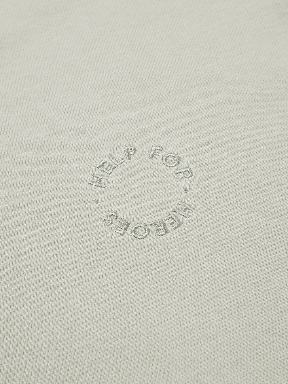 Close up of embroidered circular Help for Heroes logo on grey crew neck tshirt