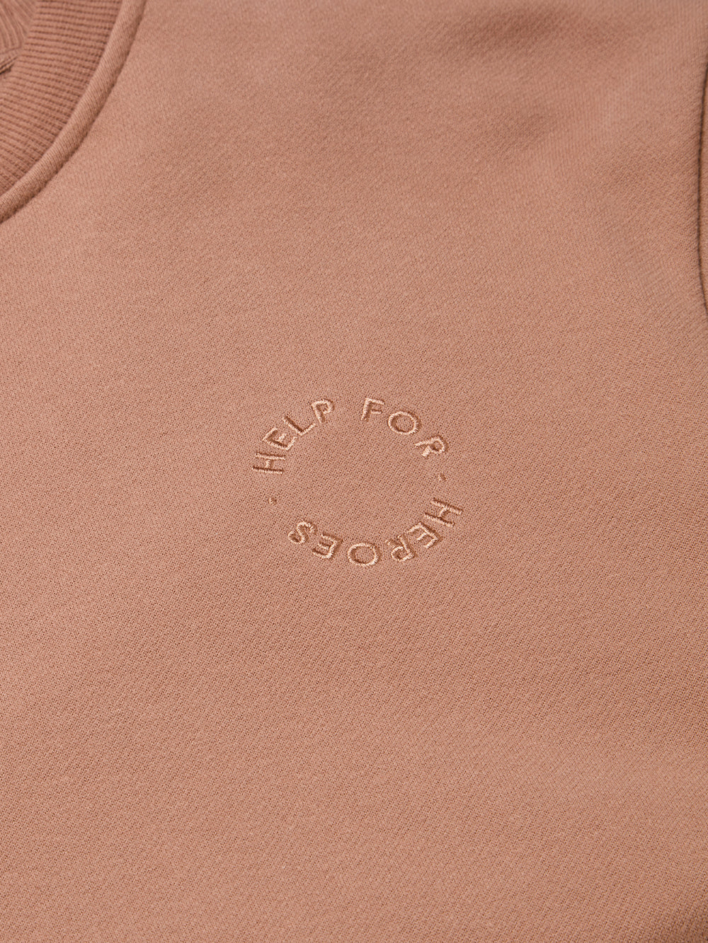 Close up of embroidered circular Help for Heroes logo on chest of the mocha pullover sweatshirt