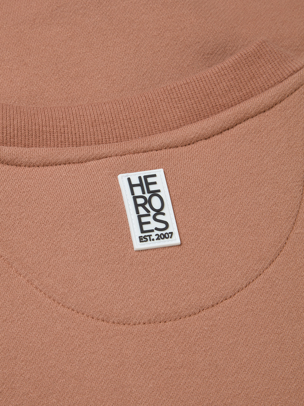 Close up of rubber Heros patch on back neck of mocha pullover Help for Heroes sweatshirt