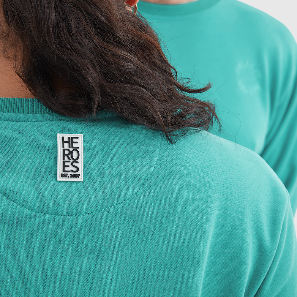 Close up of rubber Heros logo on the back neck of the Help for Heroes pullover sweatshirt in turquoise