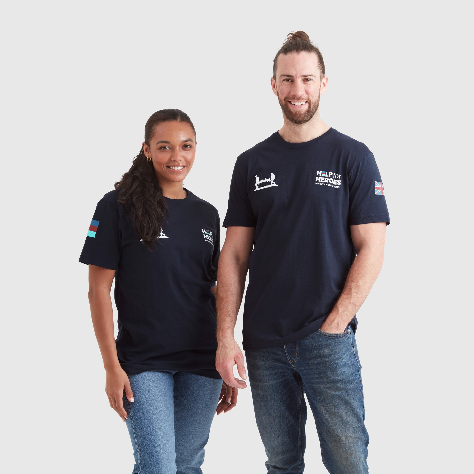 Two models, one female and one male, wearing navy crew neck t-shirts with 'Help for Heroes' logo and flag print on the sleeves.