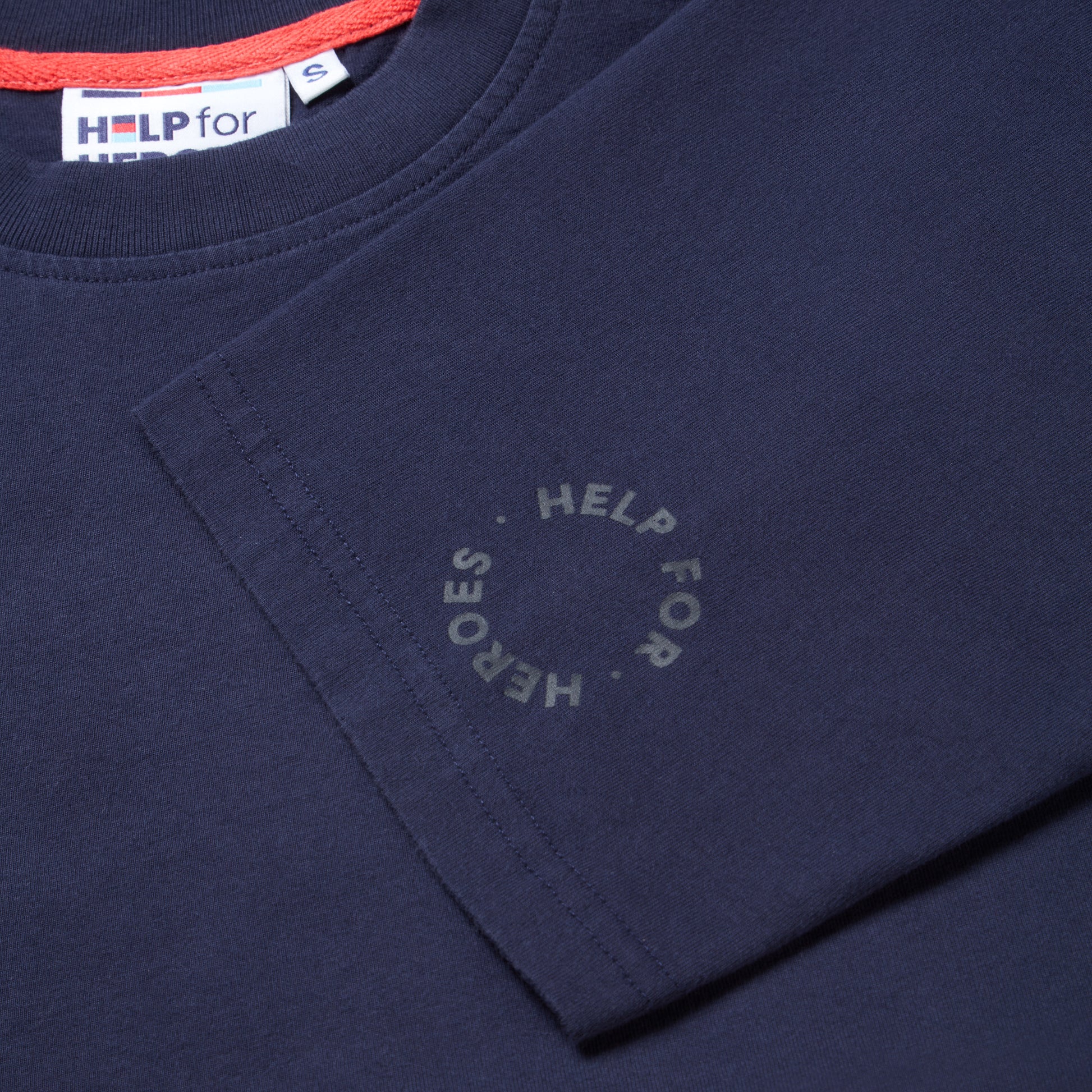 Close up sleeve detail of a circular Help for Heroes logo on a navy t-shirt