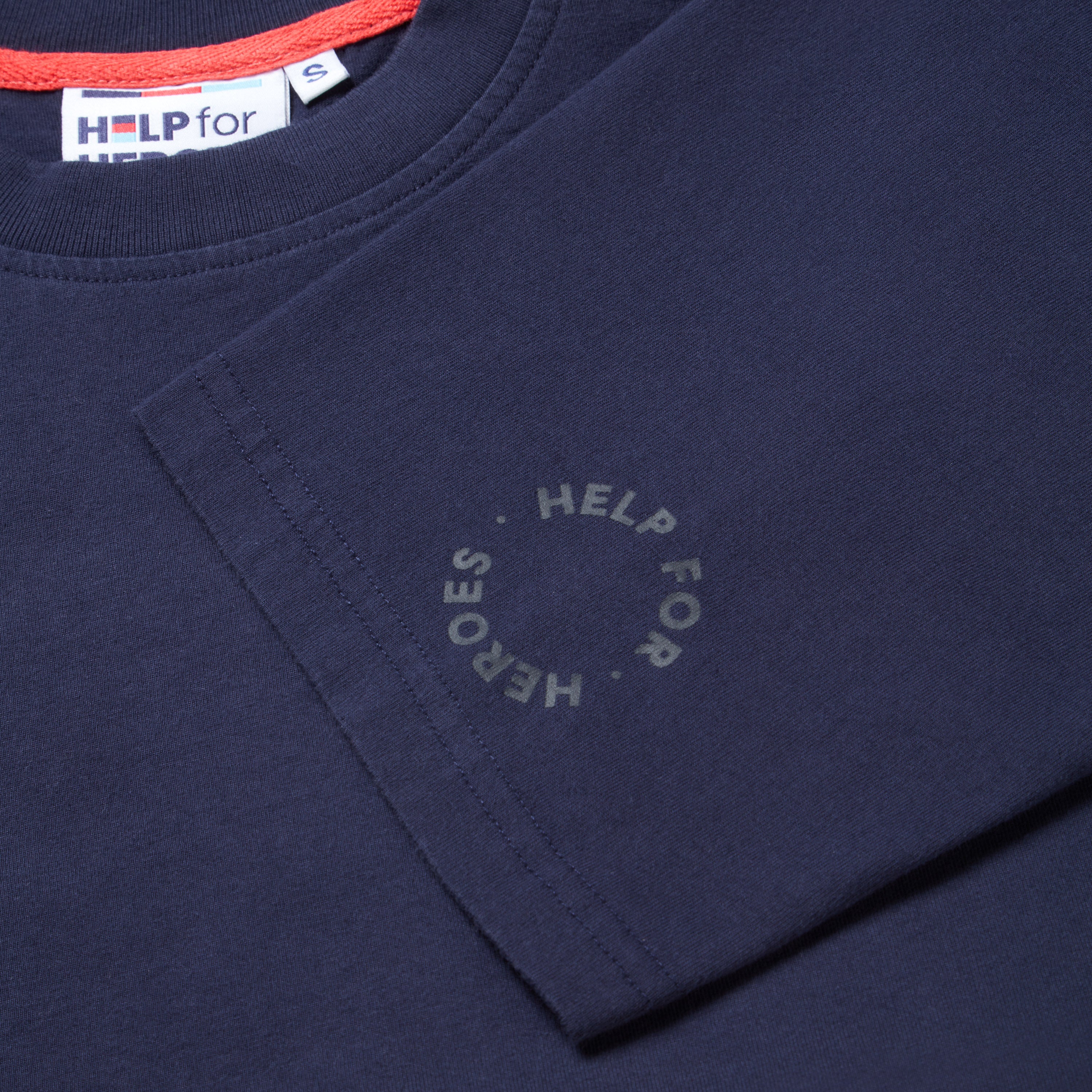 Close up sleeve detail of a circular Help for Heroes logo on a navy t-shirt