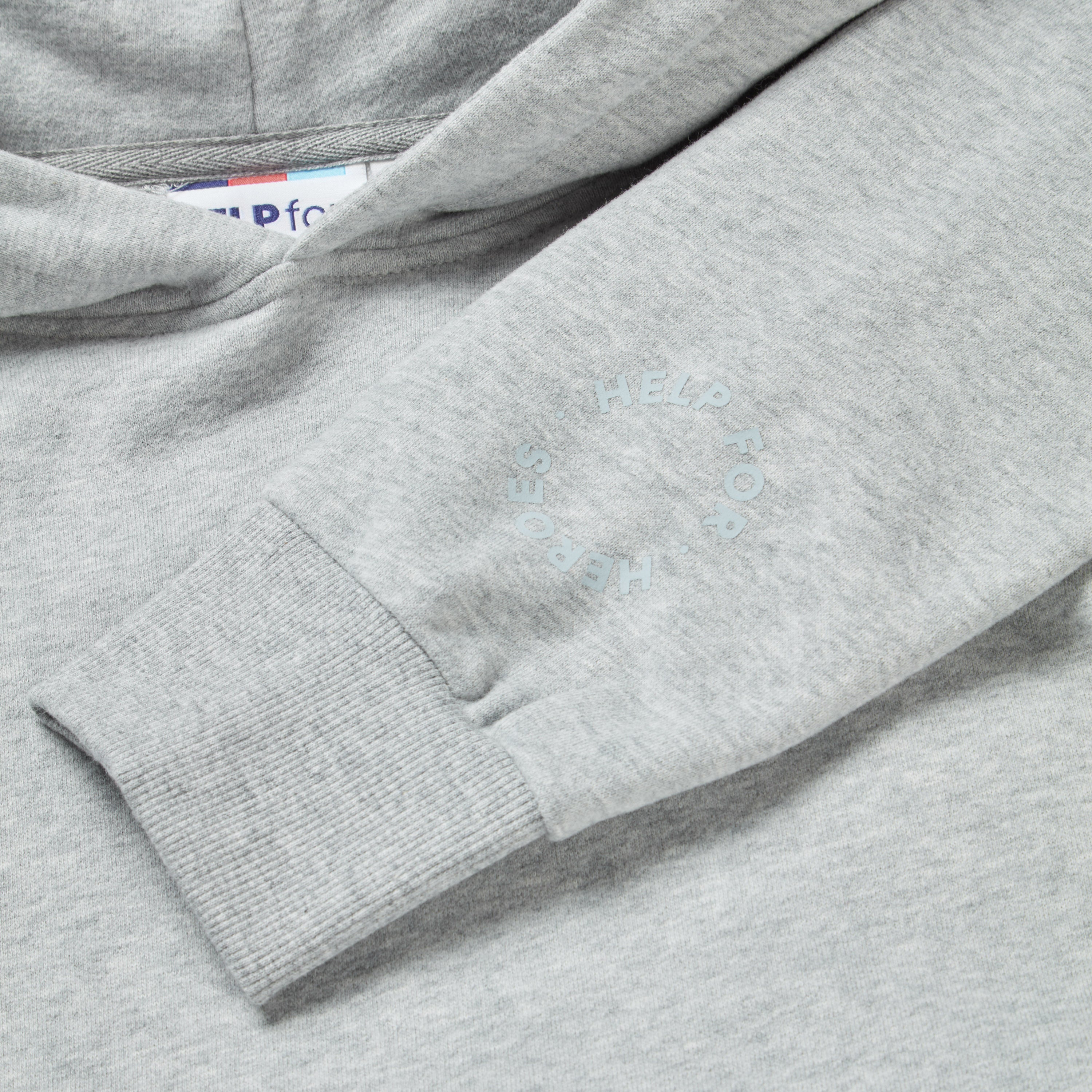 Close up image of a grey marl pullover hoodie with the text "redefine your path" and a mountain scene back print. Sleeve detail featuring a circular Help for Heroes logo