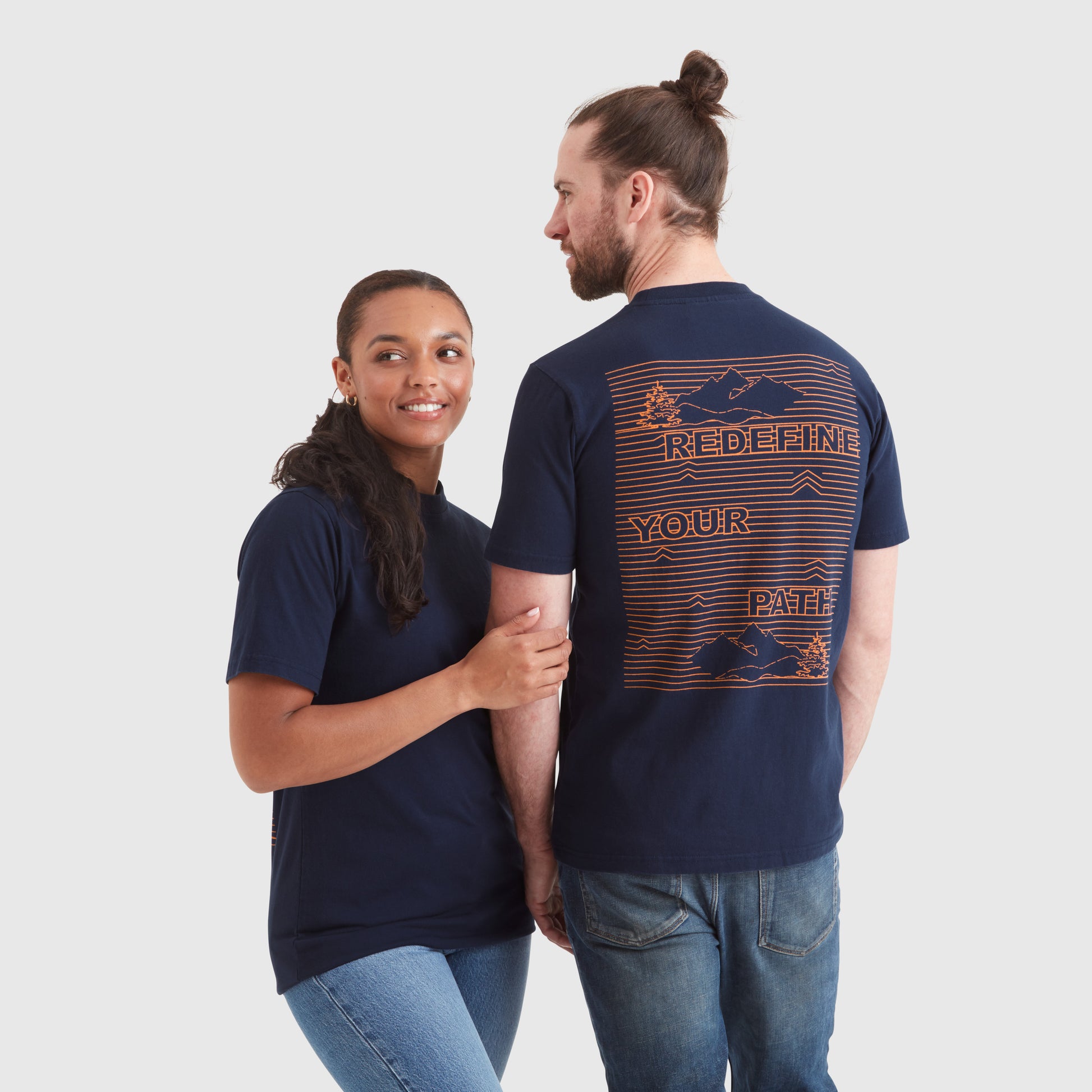 Models wearing a navy blue crew neck t-shirt with a "redefine your path" contrast slogan mountain back print in orange. Featuring a circular Help for Heroes logo on the sleeve