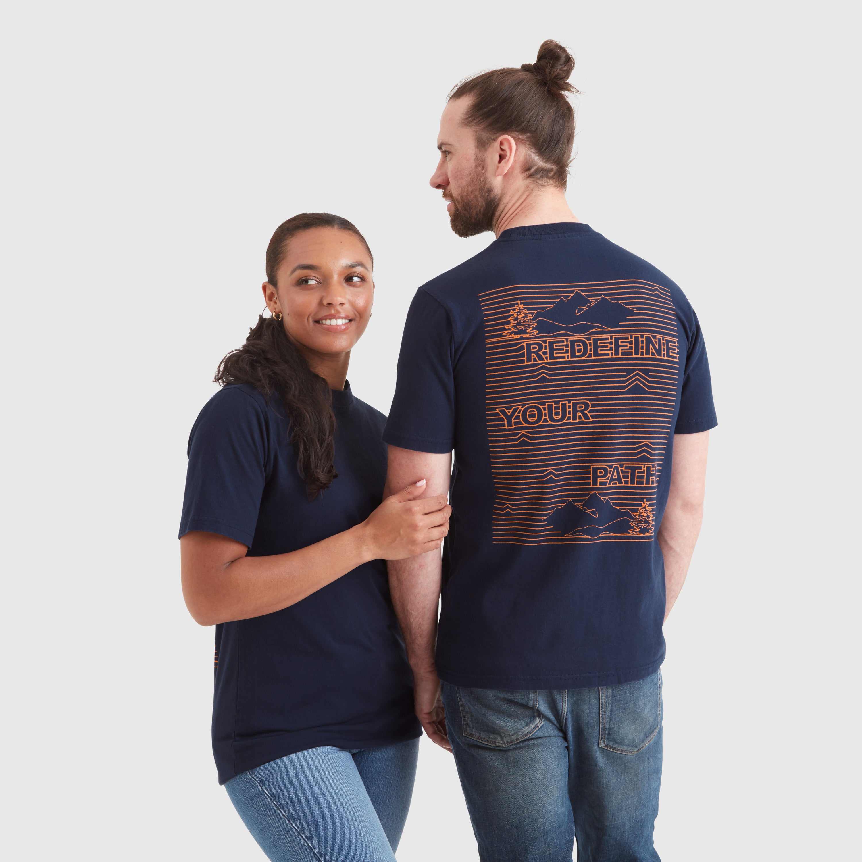 Models wearing a navy blue crew neck t-shirt with a "redefine your path" contrast slogan mountain back print in orange. Featuring a circular Help for Heroes logo on the sleeve