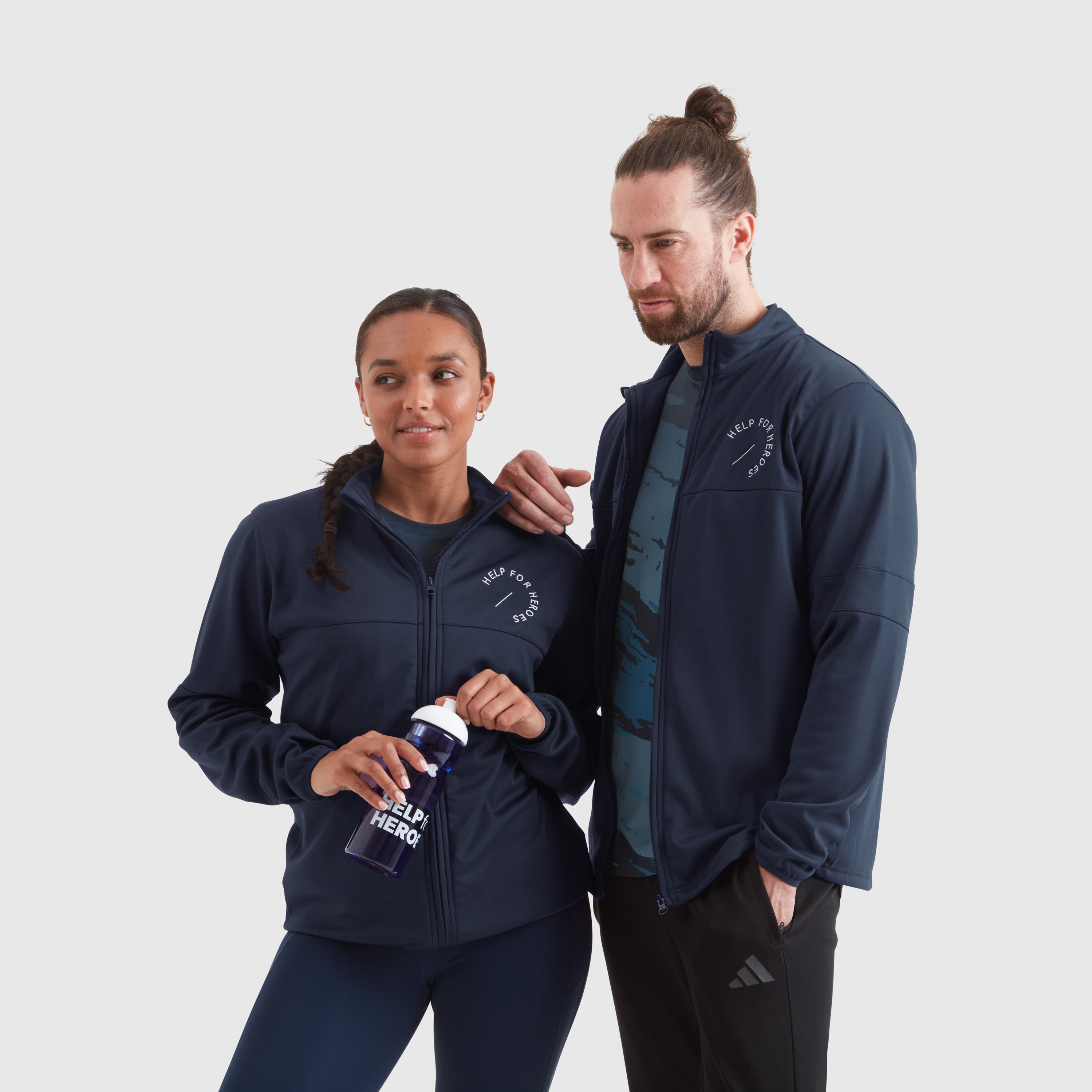 Two models wearing navy full-zip track sport leisure jackets with a Help for Heroes white logo on the chest