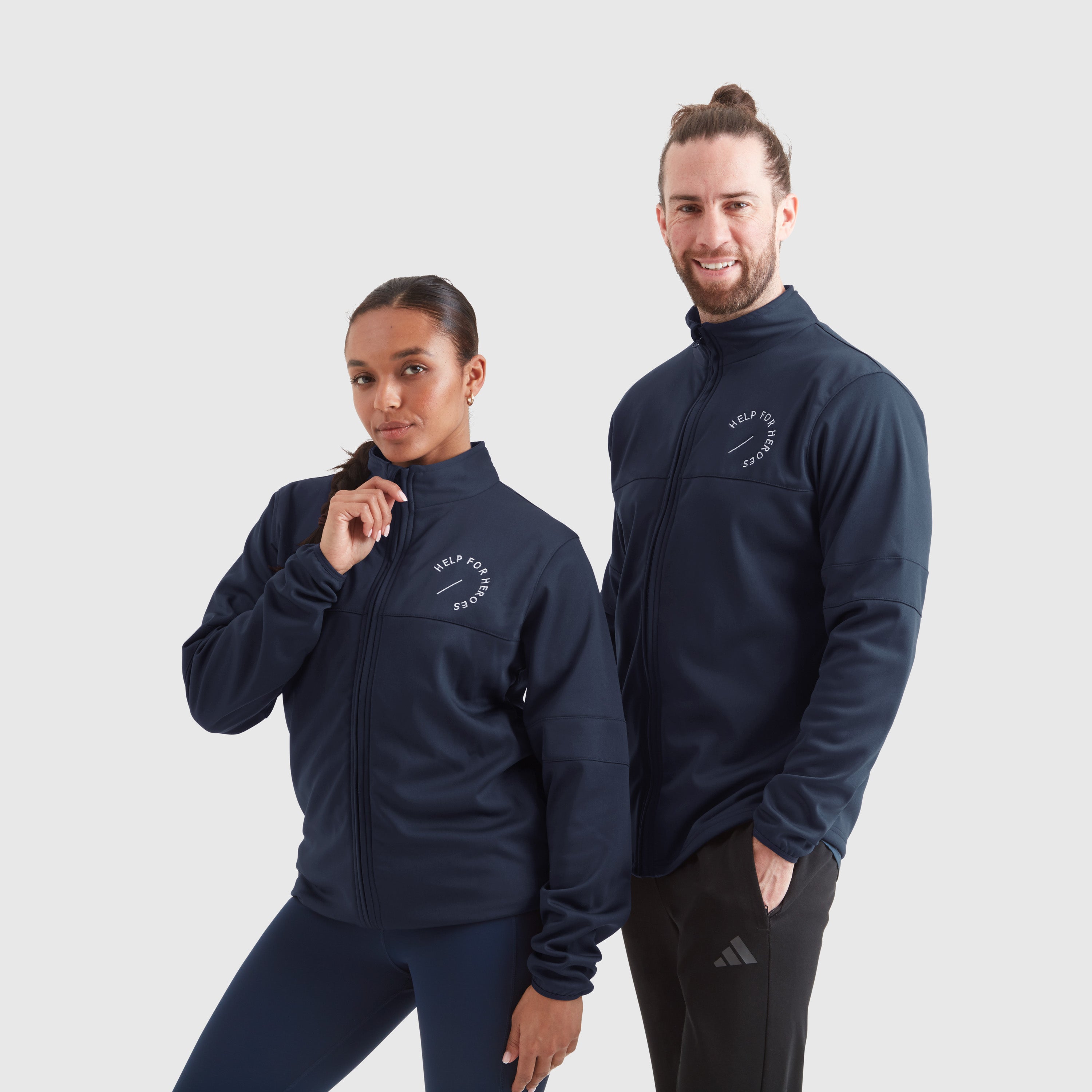 Two models wearing navy full-zip track sport leisure jackets with a Help for Heroes white logo on the chest