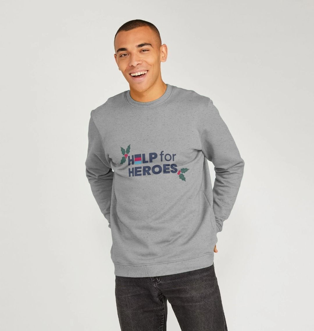 Model wearing a grey sweatshirt with Christmas Help for Heroes logo printed on the front, featuring holly leaf design