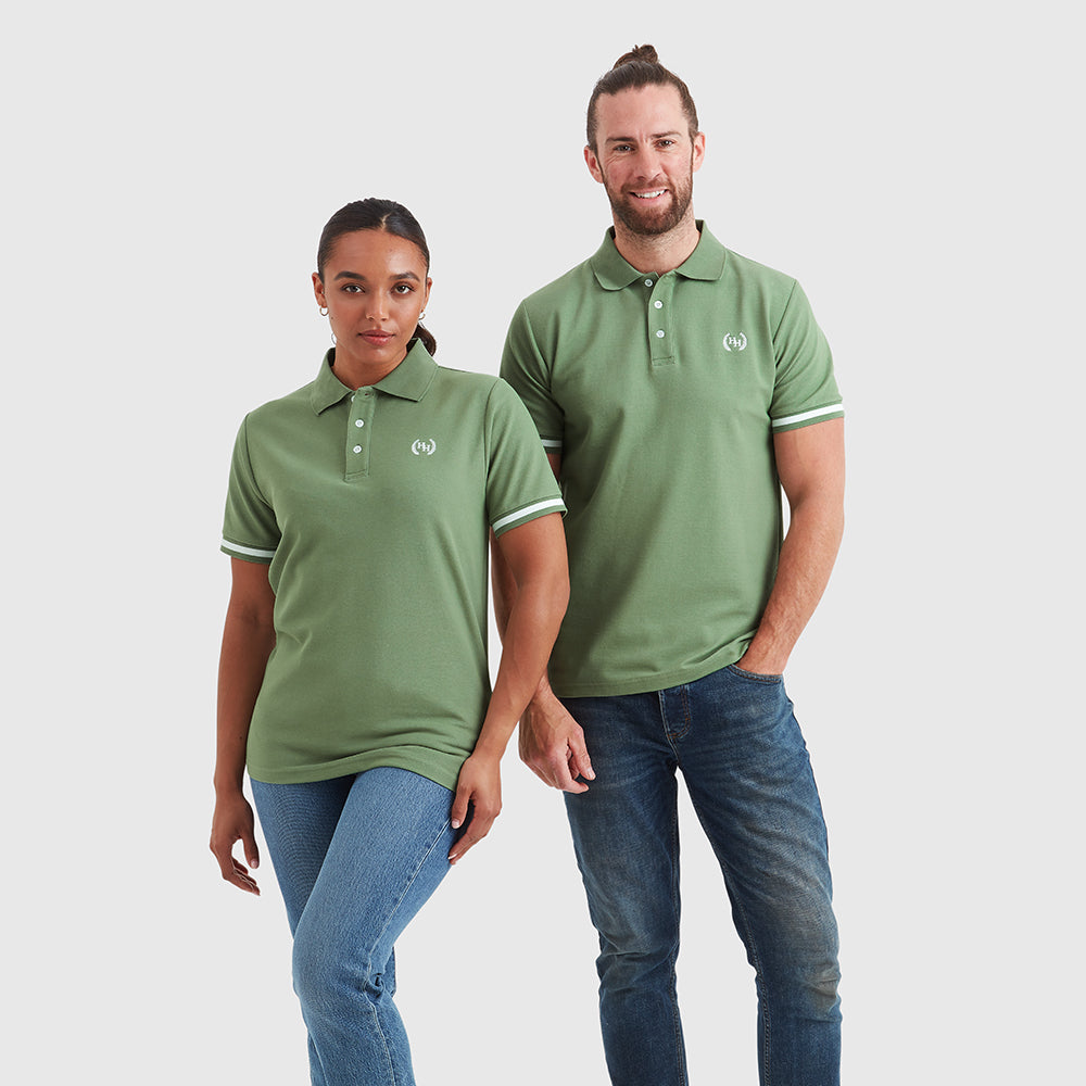 Two models wearing a olive greenpique fabric polo shirt with an embroidered help for heroes wreath logo on the chest, tipping on the cuffs, and branded buttons.