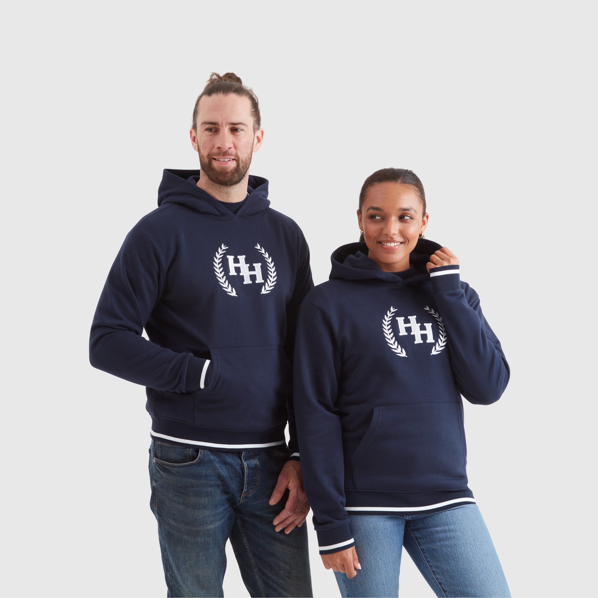 Two models wearing navy blue pullover hoodies with a Help for Heroes wreath logo design on the chest and tipped detailing to cuffs