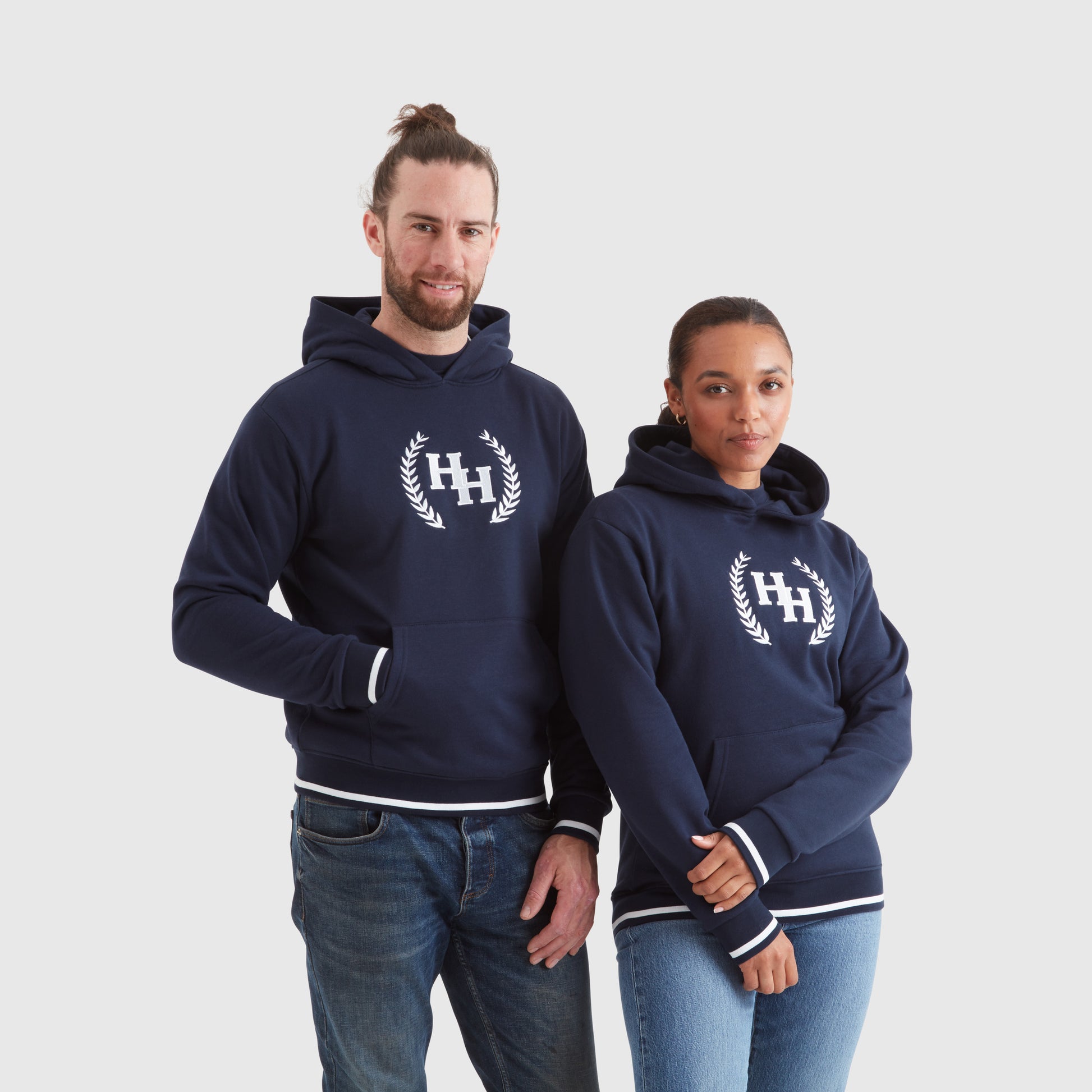Two models wearing navy blue pullover hoodies with a Help for Heroes wreath logo design on the chest and tipped detailing to cuffs