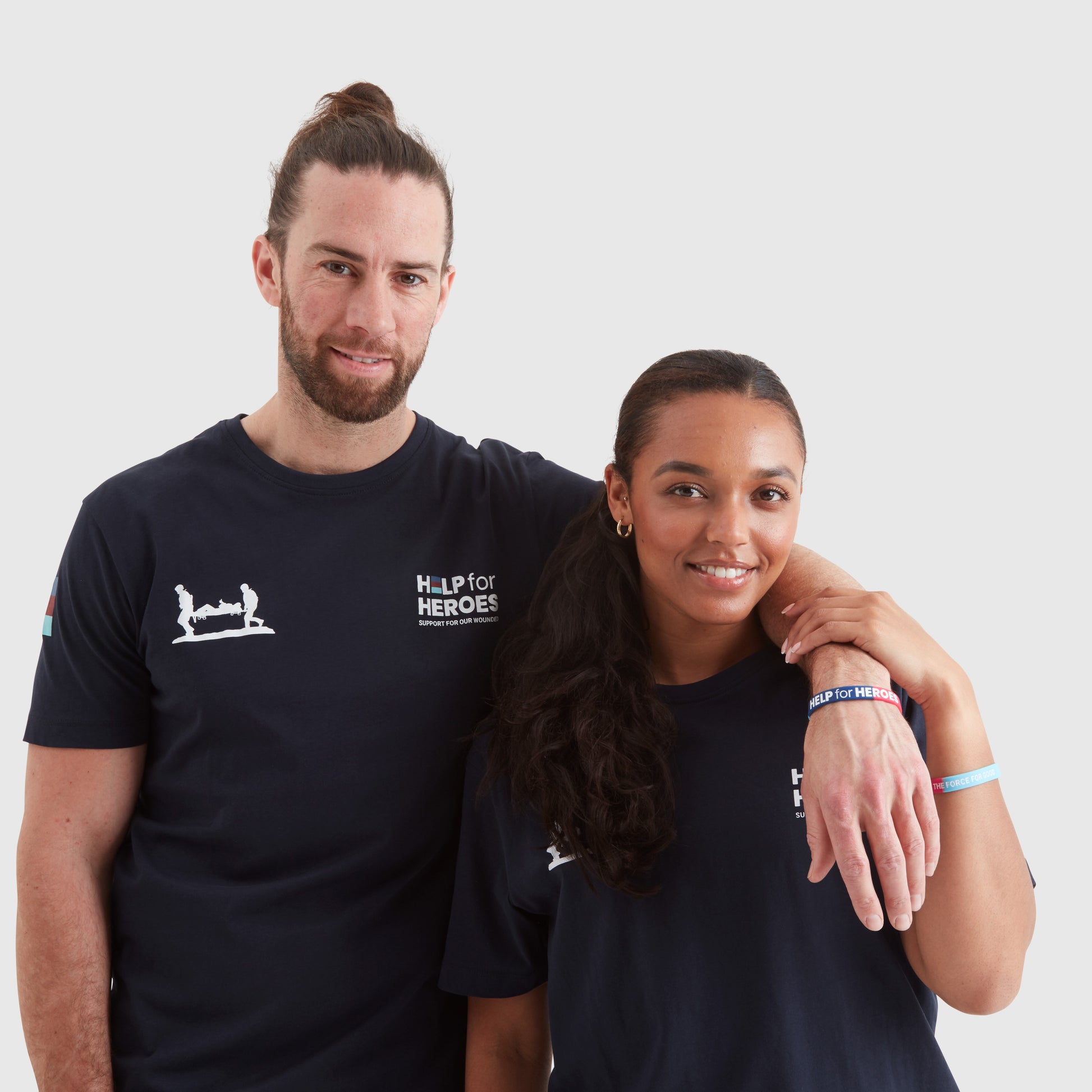 Two models wearing silicone tri colour wristbands featuring the Help for Heroes logo in white text