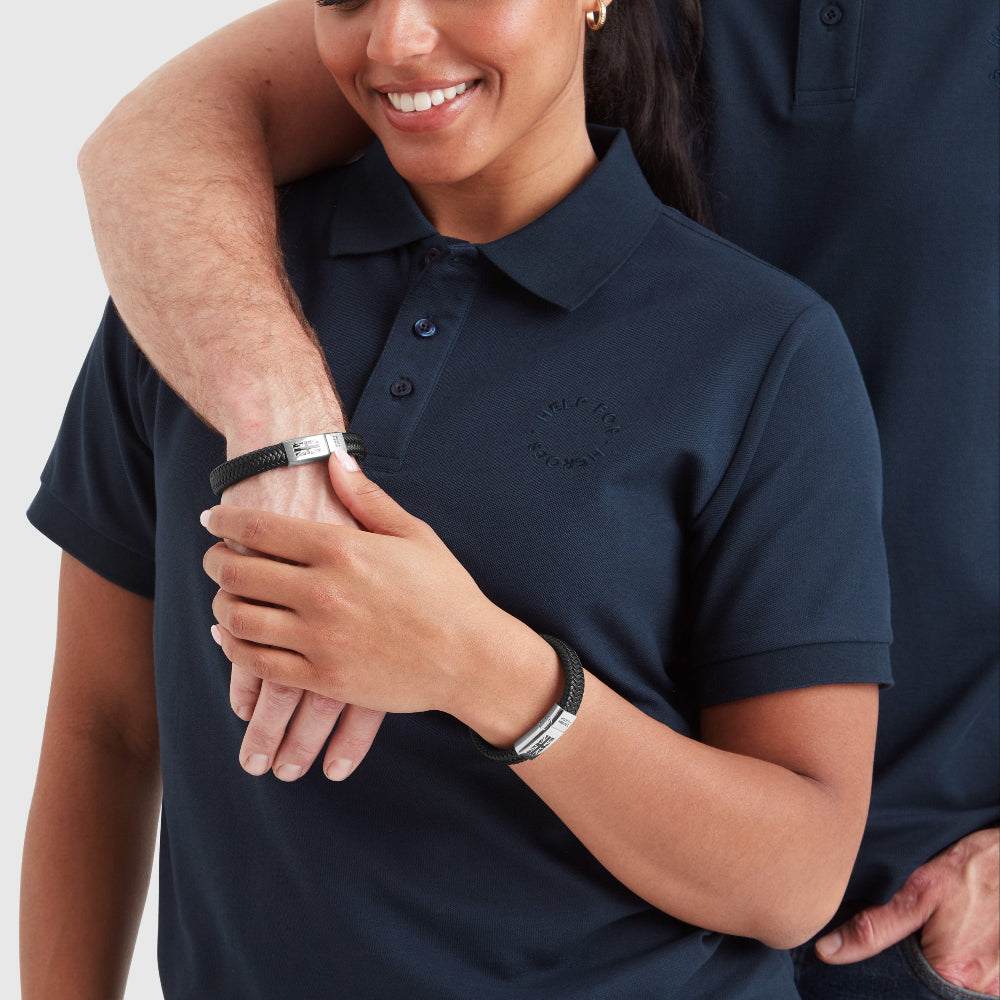 A model wearing a black leather chunky bracelet with a clasp featuring the Union Jack flag and the 'Help for Heroes' logo.
