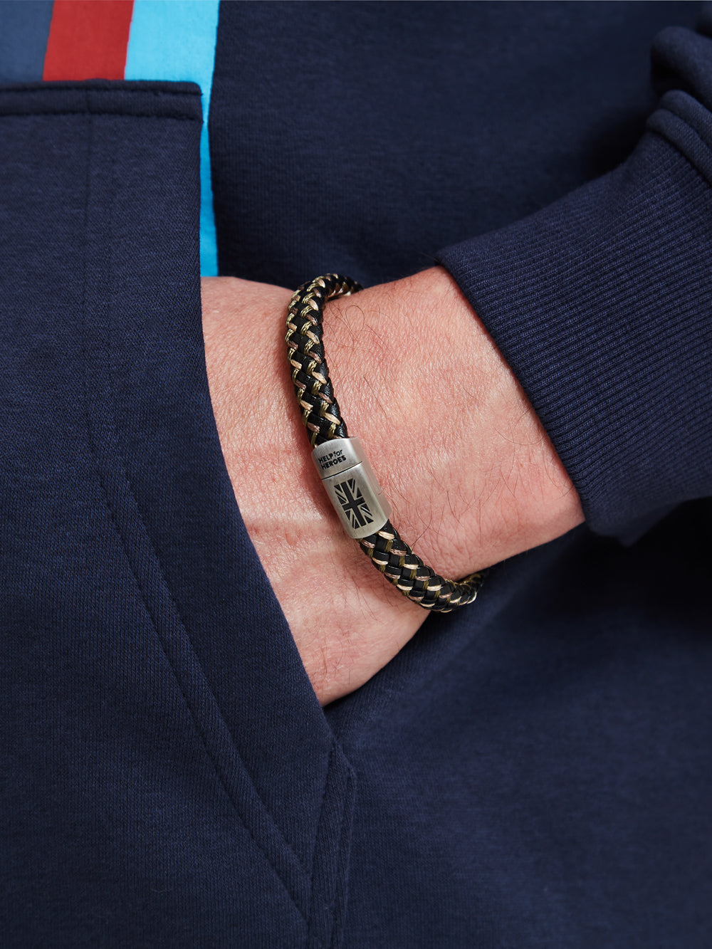 Help for heroes camo wristband on model's wrist. Featuring metal clasp with union jack and logo