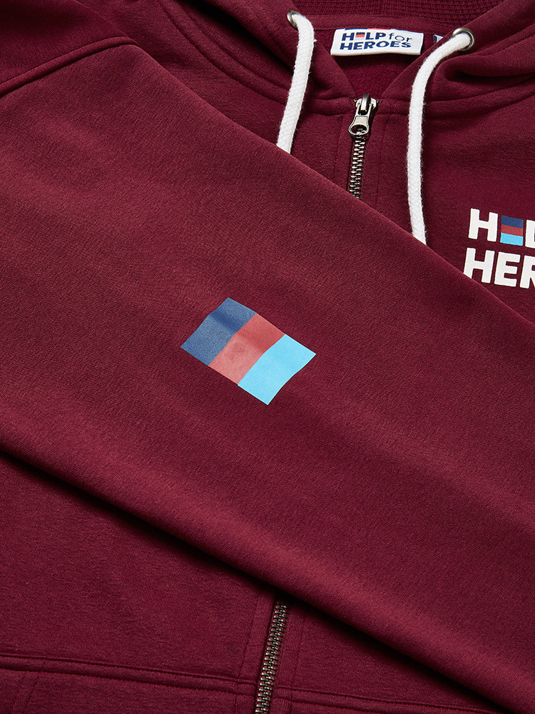 Close up image of tri colour logo printed on sleeve of burgundy zipped hoody featuring printed Help for Heroes logo on the front and Stretcher Bearer logo on the back. Union Jack flag printed on sleeve