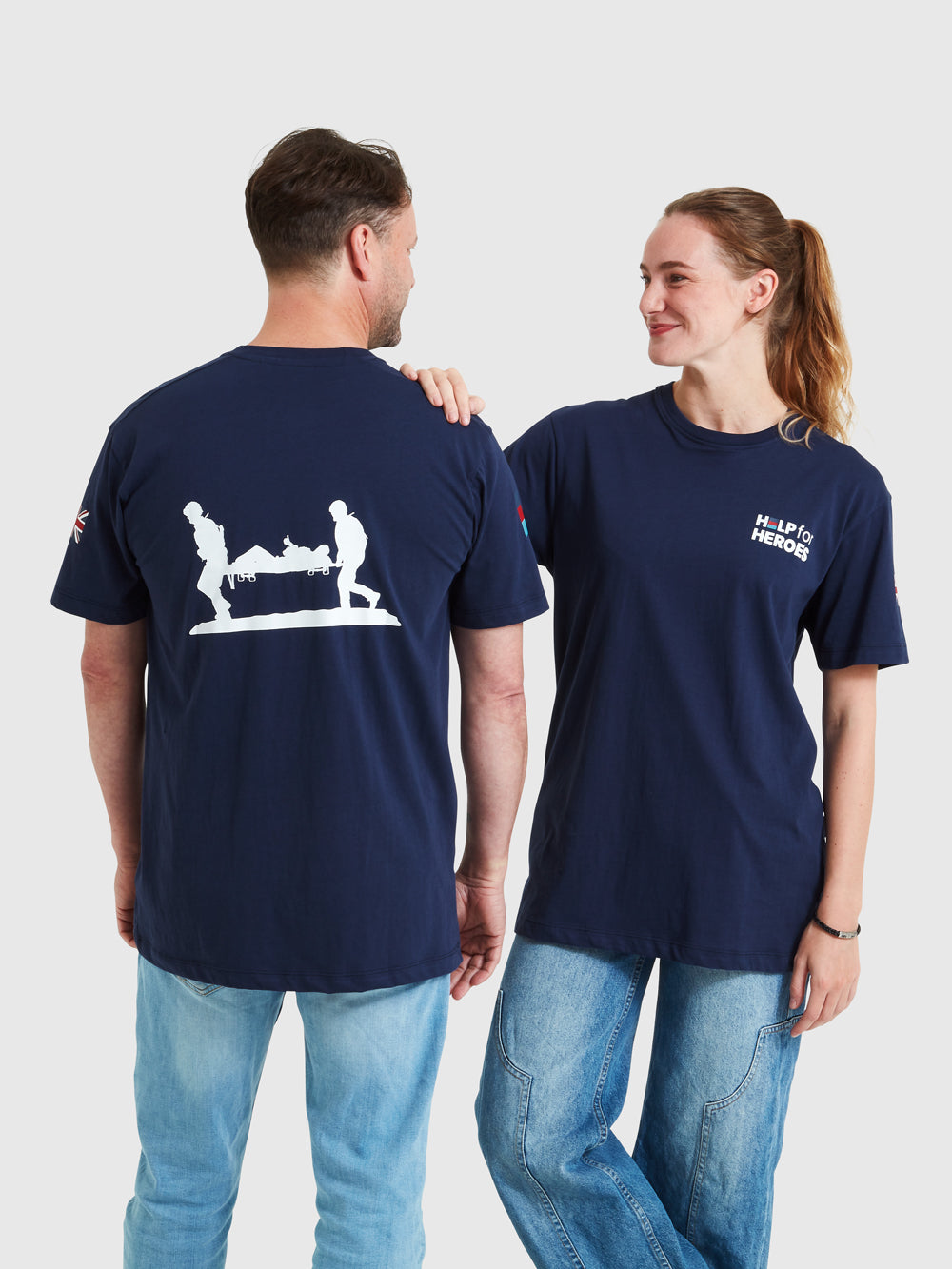 Two models wearing navy t-shirts, featuring the Help for Heroes logo, tri colour and union jack flags and stretcher bearer logo printed on the back