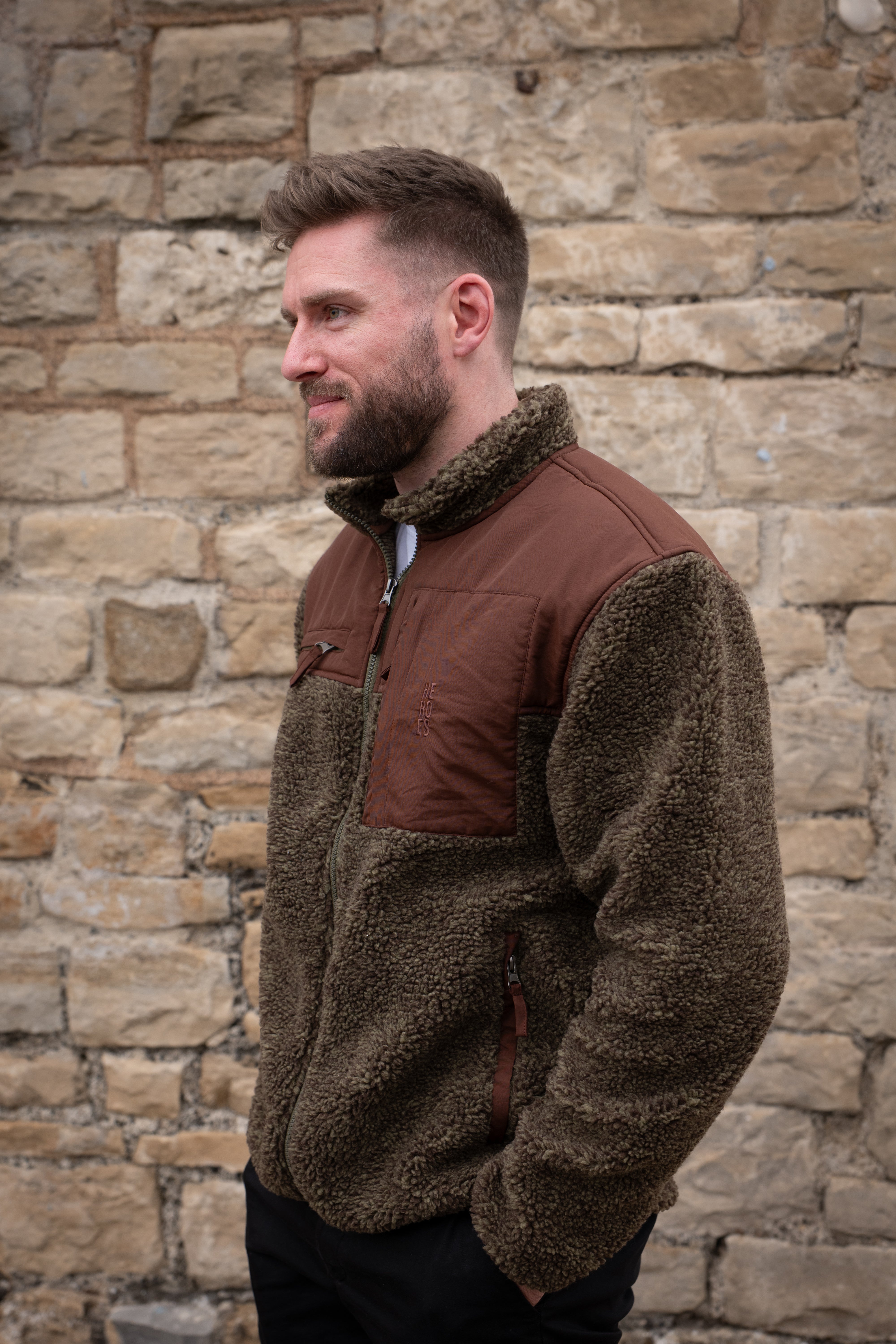 Model wearing heavyweight fleece jacket in brown, featuring chest pockets and Help for Heroes logo