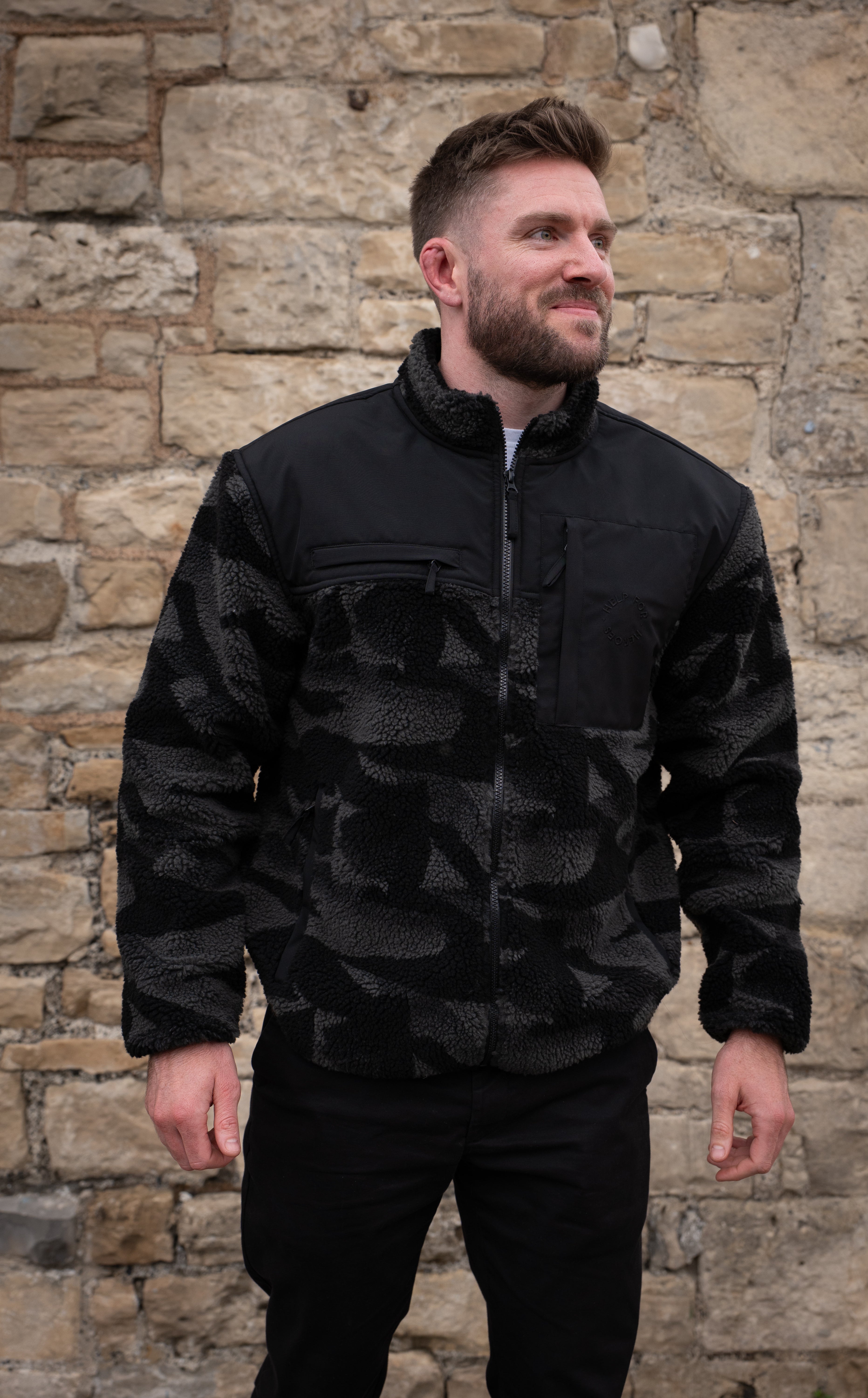 Model wearing heavyweight fleece jacket in grey camo, featuring chest pockets and Help for Heroes logo
