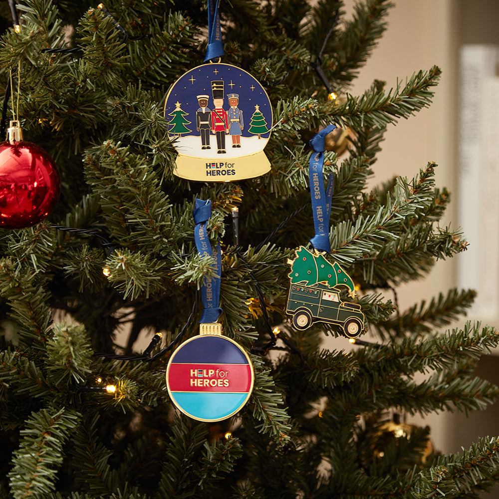 Xmas tree showing three Help for Heroes enamel Christmas decorations. Featuring military characters in a snow glove, a land rover and a tri-colour bauble