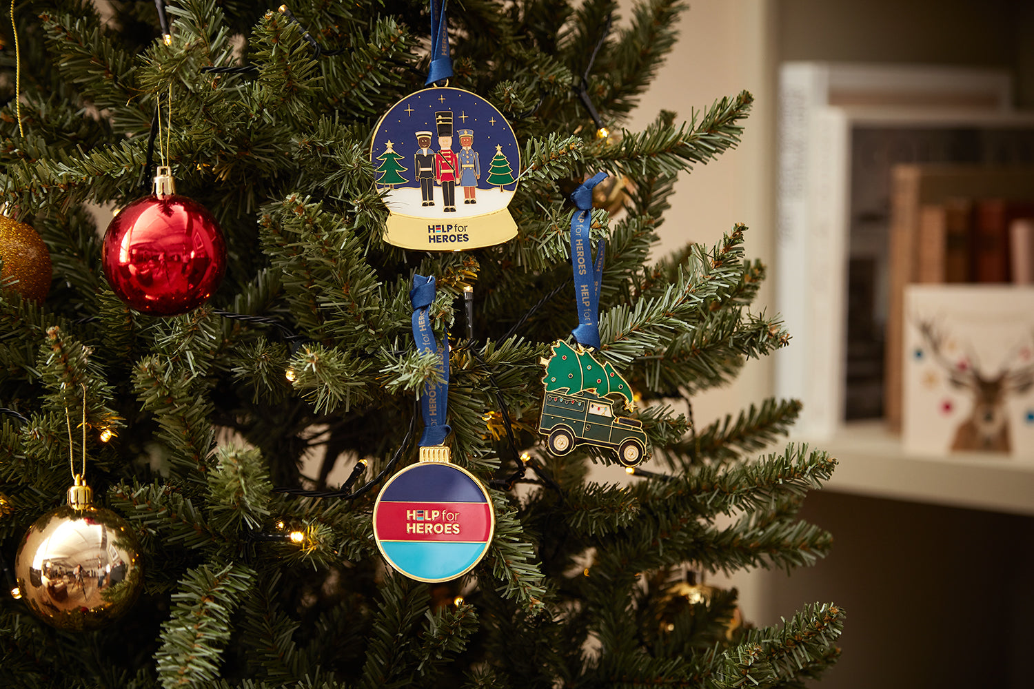 Xmas tree showing three Help for Heroes enamel Christmas decorations. Featuring military characters in a snow glove, a land rover and a tri-colour bauble