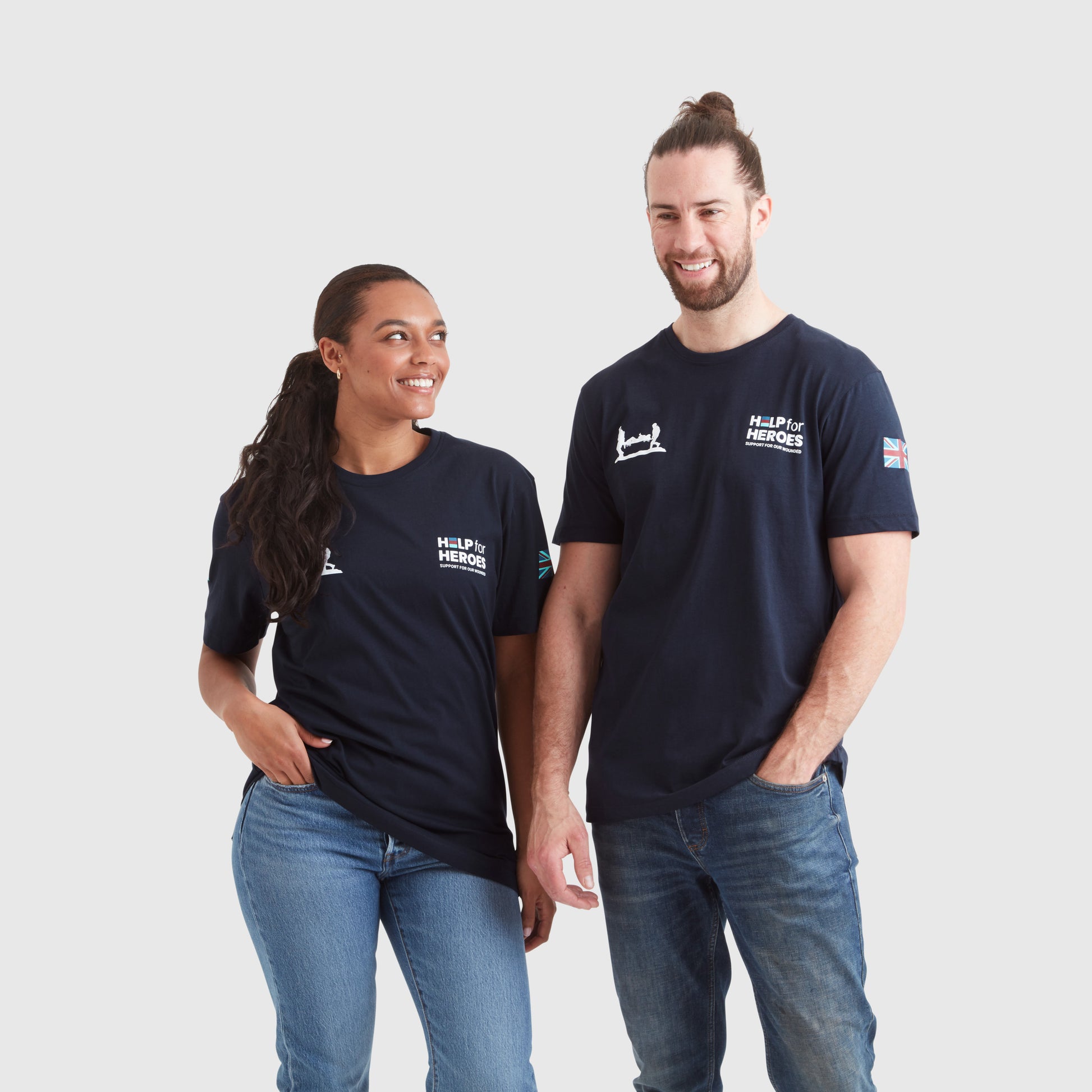 Two models, one female and one male, wearing navy crew neck t-shirts with 'Help for Heroes' logo and flag print on the sleeves.