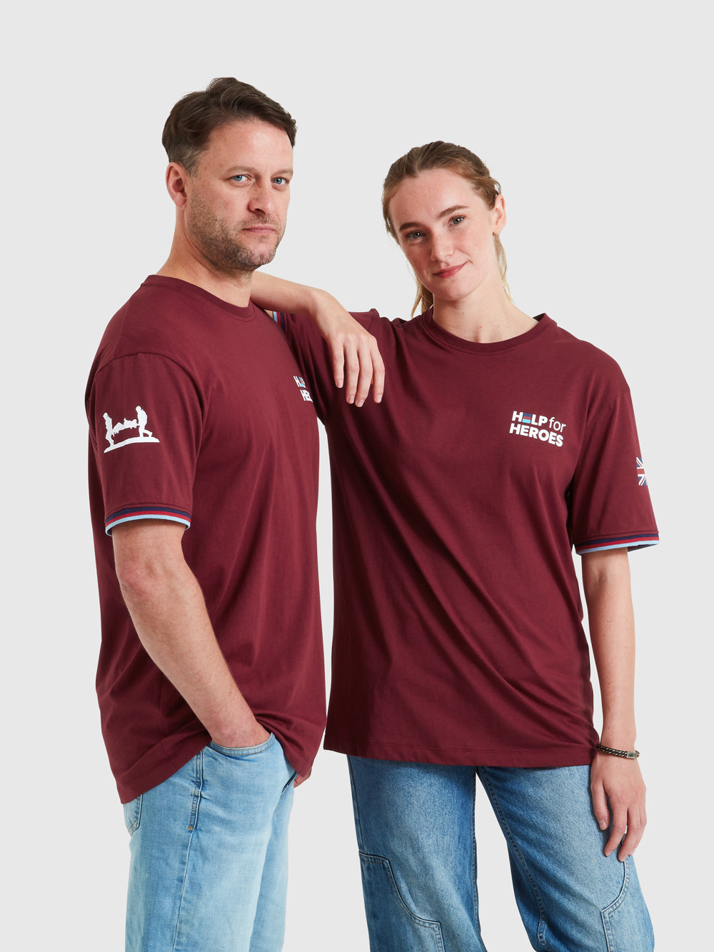 Two models wearing burgundy shirts with Help for Heroes logo printed on chest. Also features stretcher bearer logo and Union Jack flag on sleeves. Tri colour tipped sleeves.