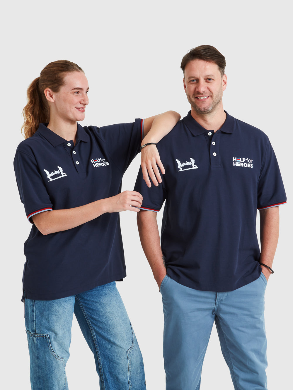Two models wearing navy polo shirts which feature Help for Heroes logo, Stretcher Bearer logo and tri colour tipped sleeves