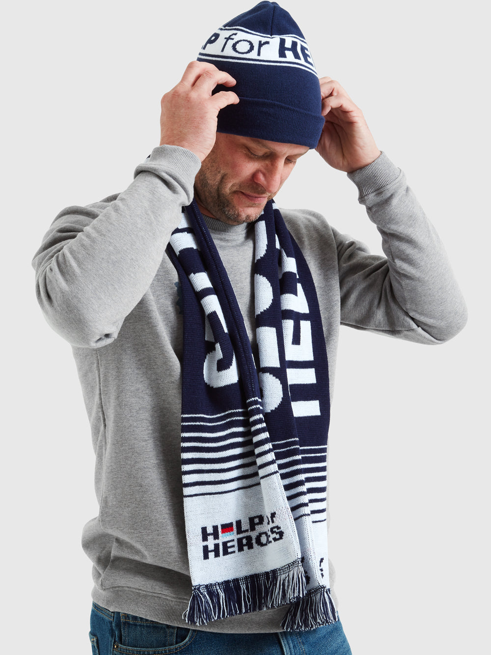 Model wearing navy scarf which features Help for Heroes logo and writing in white text