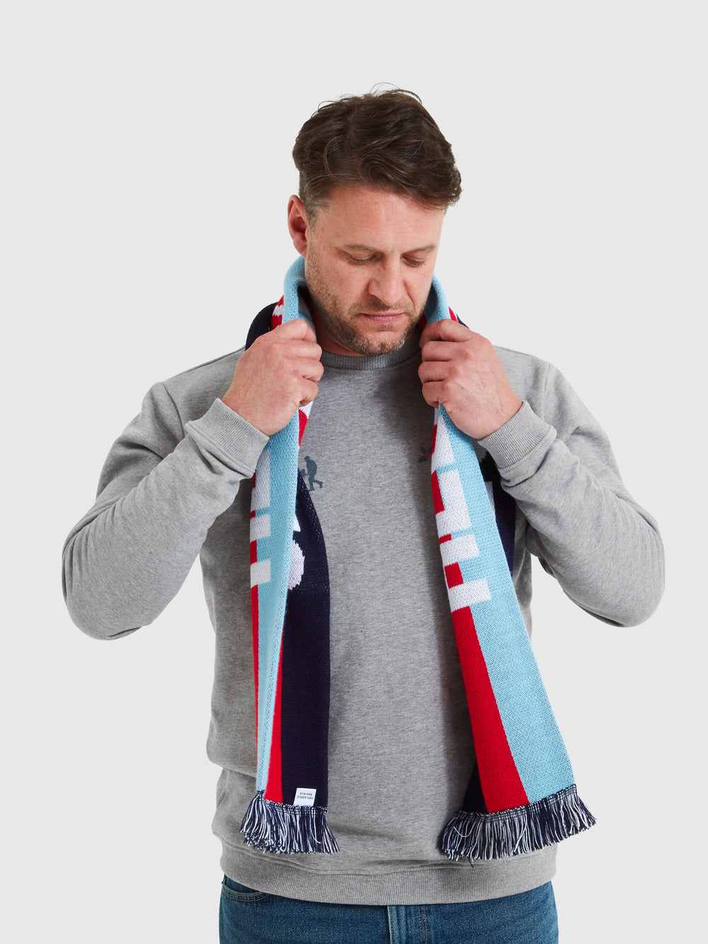 Image of male model wearing Help for Heroes tri colour scarf, featuring a stripe design with Help for Heroes written in white